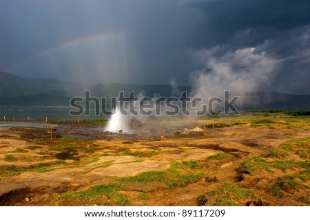 Landscape with lake by hot springs with water steam and rainbow