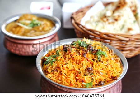 Set of Indian food. Biryani in the front bowl. Curry and naan bread at the back. Indian cuisine consists of a wide variety of regional and traditional cuisines native to the Indian subcontinent.