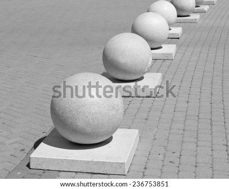 Protection in the form of decorative stone spheres on sidewalk. Black and white