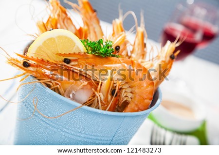 Bucket of king prawns on ice with lemon, sauce and two glasses of wine