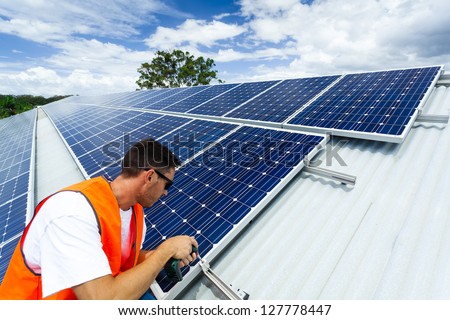 Young technician installing solar panels on factory roof