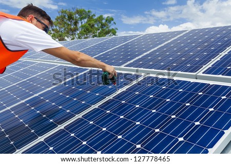 Technician installing solar panels on factory roof