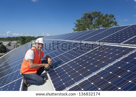 Young technician installing solar panels on factory roof