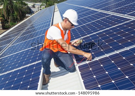 Young technician checking solar panels on factory roof