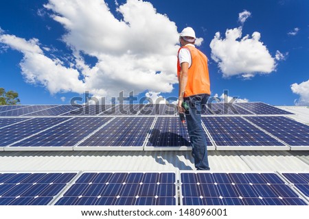Young technician checking solar panels on factory roof