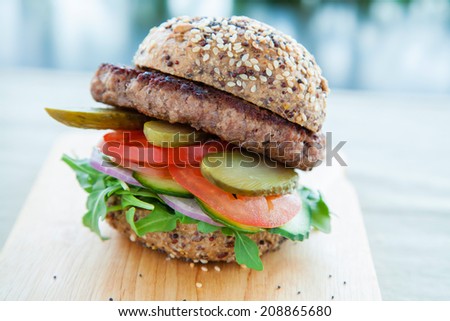 Lean beef burger with rocket, pickles, tomato and onions
