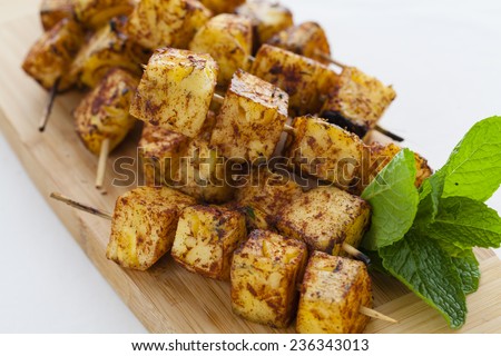 Cinnamon covered grilled pineapple skewers on chopping board