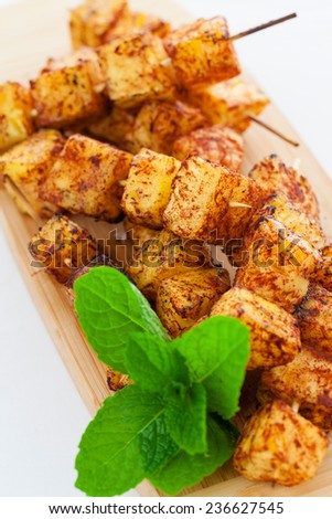 Cinnamon covered grilled pineapple skewers on chopping board