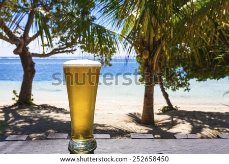 Cold beer on tropical beach with coconut palms