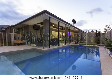 Swimming pool and outdoor entertaining area in stylish home at dusk