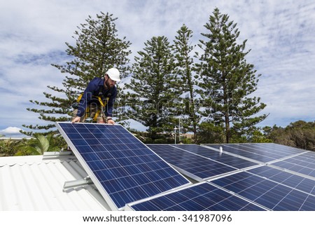 Solar panel technician installing solar panels on roof