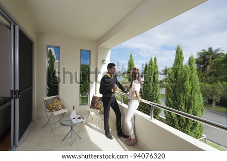 Young couple toasting with champagne on a modern backyard overlooking the city