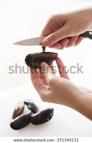 hand using knife to take off scallop hair