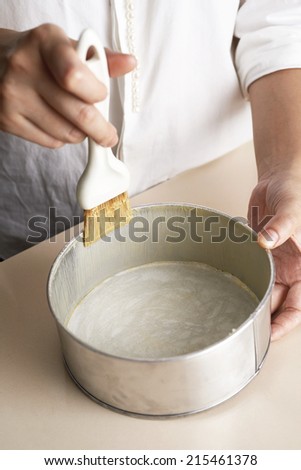 Hand brushing butter inside cake tray