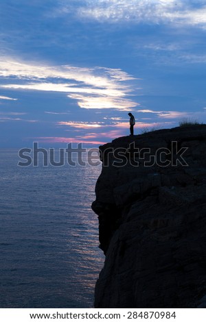 Silhouette of sad people on cliff