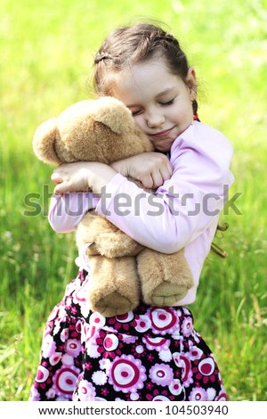 Image of pretty little girl hugging her teddy bear in park