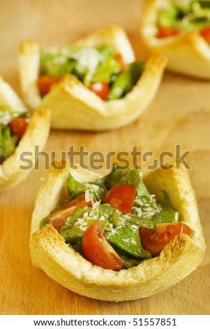 Salad with tomatoes and grated cheese in tartlets from bread slices