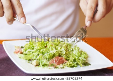 Man, eating Caesar salad with salmon