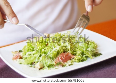 Man, eating Caesar salad with salmon