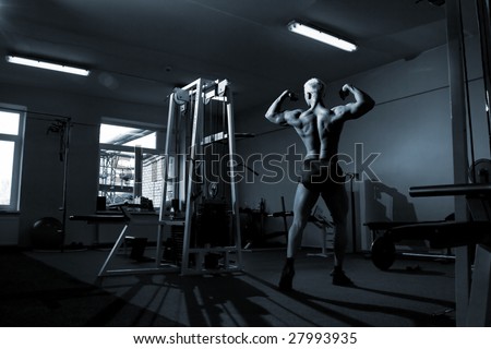 Muscular man is posing in the gym