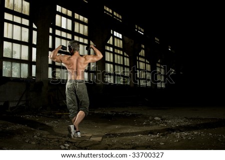 Muscular man is posing in industrial place