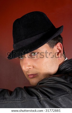 Close-up of a young man in a trilby looking over shoulder