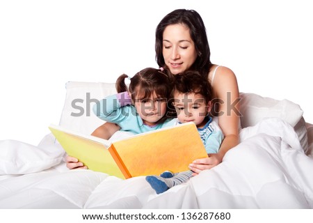 Mother reading bed time story book to daughter and son kids in bed isolated Mother reading bed time story book to daughter and son kids in bed isolated