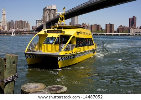 New York City\'s water taxi arriving at Fulton Ferry landing in Brooklyn. Here seen with the Brooklyn Bridge in the background on a bright sunny day with a depp blue sky.