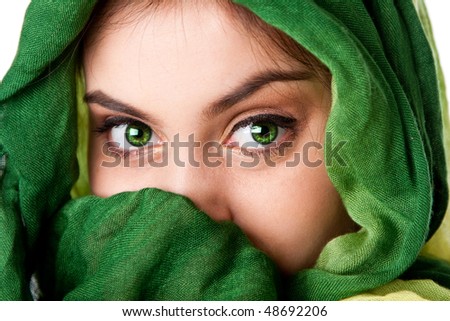 Portrait of mysterious beautiful Caucasian Hispanic Latina woman face with green penetrating eyes and green fashion scarf wrapped around head and mouth covered, isolated.