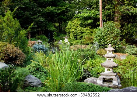 Beautiful peaceful Japanese zen garden used for meditation and relaxation, filled with green vegetation and granite Rokkaku Yukimi Lanterns.