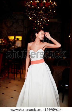 Happy beautiful sexy bride brunette girl woman in white wedding dress with hairstyle and bright makeup in interior