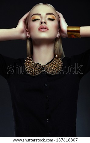 High fashion look.glamor closeup portrait of beautiful sexy stylish blond  young woman model with bright yellow makeup  with perfect clean skin with gold jewelery in black cloth