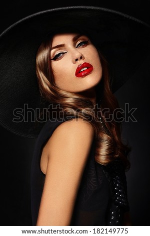 High fashion look.glamor closeup portrait of beautiful sexy stylish Caucasian young woman model with bright makeup, with red lips, with perfect clean skin in big black hat