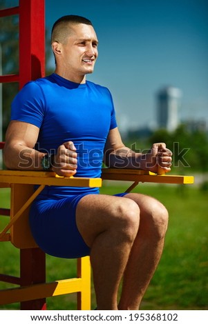 Handsome healthy happy srtong athlete male man exercising at the city park - fitness concepts on a beautiful summer day on horizontal bar