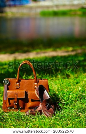 Retro brown shoes and man leather bag in bright colorful summer grass in the park