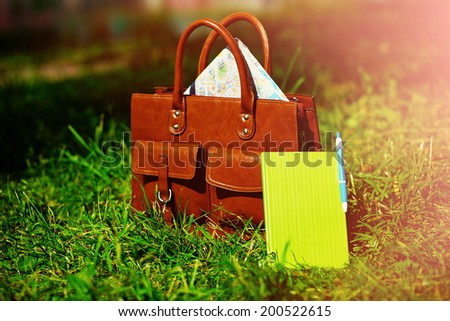 Retro brown  man leather bag and notebook in bright colorful summer grass in the park