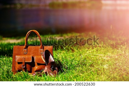 Retro brown shoes and man leather bag in bright colorful summer grass in the park