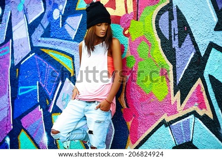 portrait of sexy urban modern young stylish woman girl  model in bright modern cloth in jeans outdoors in the street behind graffito