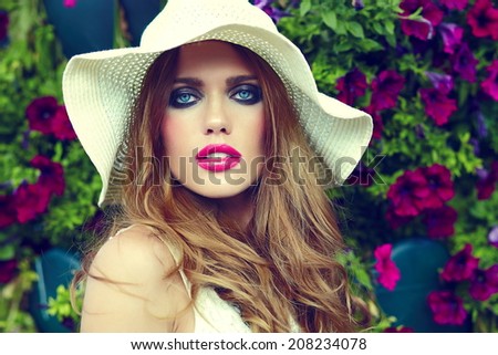 High fashion look.glamor closeup portrait of beautiful sexy stylish blond young woman model with bright makeup and pink lips with perfect clean skin in hat near summer flowers