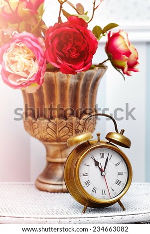 classic clock  watch in bright colorful retro interior behind red flowers