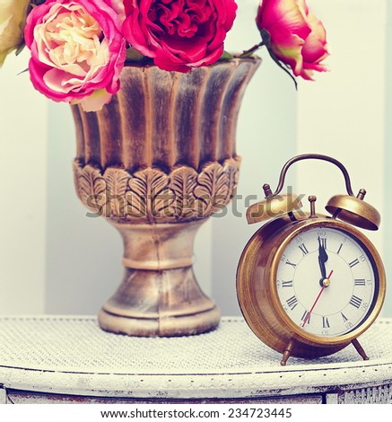 classic clock  watch in bright colorful retro interior behind red flowers