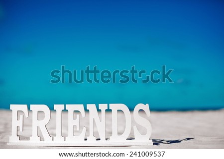 Name friends on white sand behind blue sky near ocean