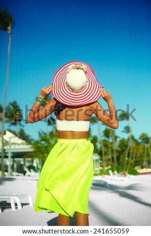 High fashion look. back of glamor sexy model girl  in colorful cloth and sunhat behind blue beach  sky