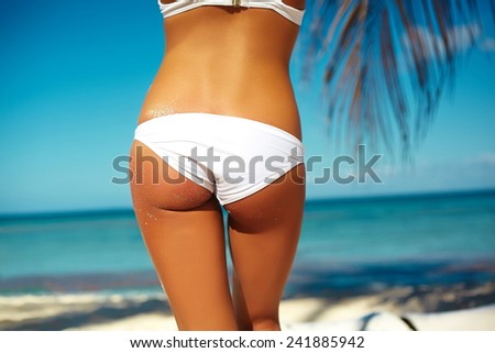 High fashion look. back of glamor sexy sunbathed model girl in white lingerie in colorful sunhat behind blue beach ocean water