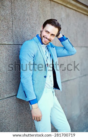 Young stylish confident happy handsome businessman model  in suit cloth lifestyle in the street standing near wall