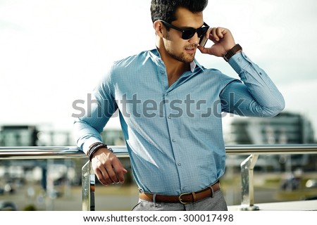 Fashion portrait of young sexy businessman handsome  model man in casual cloth suit in sunglasses in the street speaking on his phone