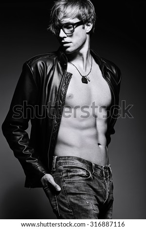 Young handsome muscled fit male model man posing in studio showing his abdominal muscles
