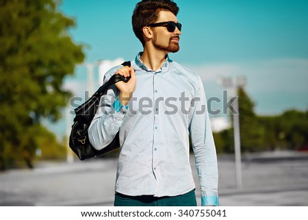 portrait of young stylish confident happy handsome  model man in hipster cloth with bag in the street, life style