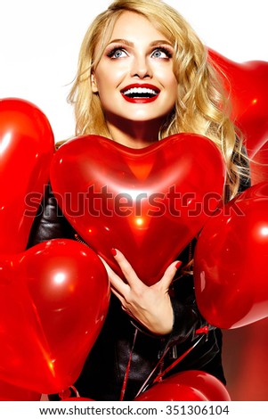 portrait of beautiful happy sweet smiling blonde woman girl holding in her hands red heart balloons in casual black hipster clothes