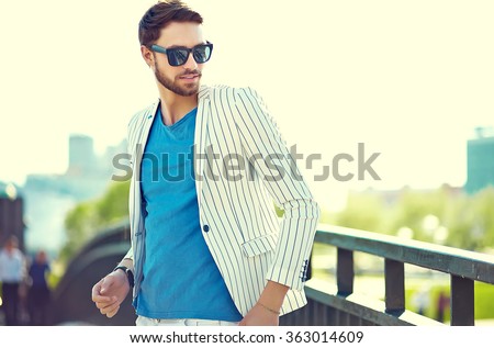 Young stylish confident happy handsome businessman model in suit hipster clothes walking in the street in sunglasses